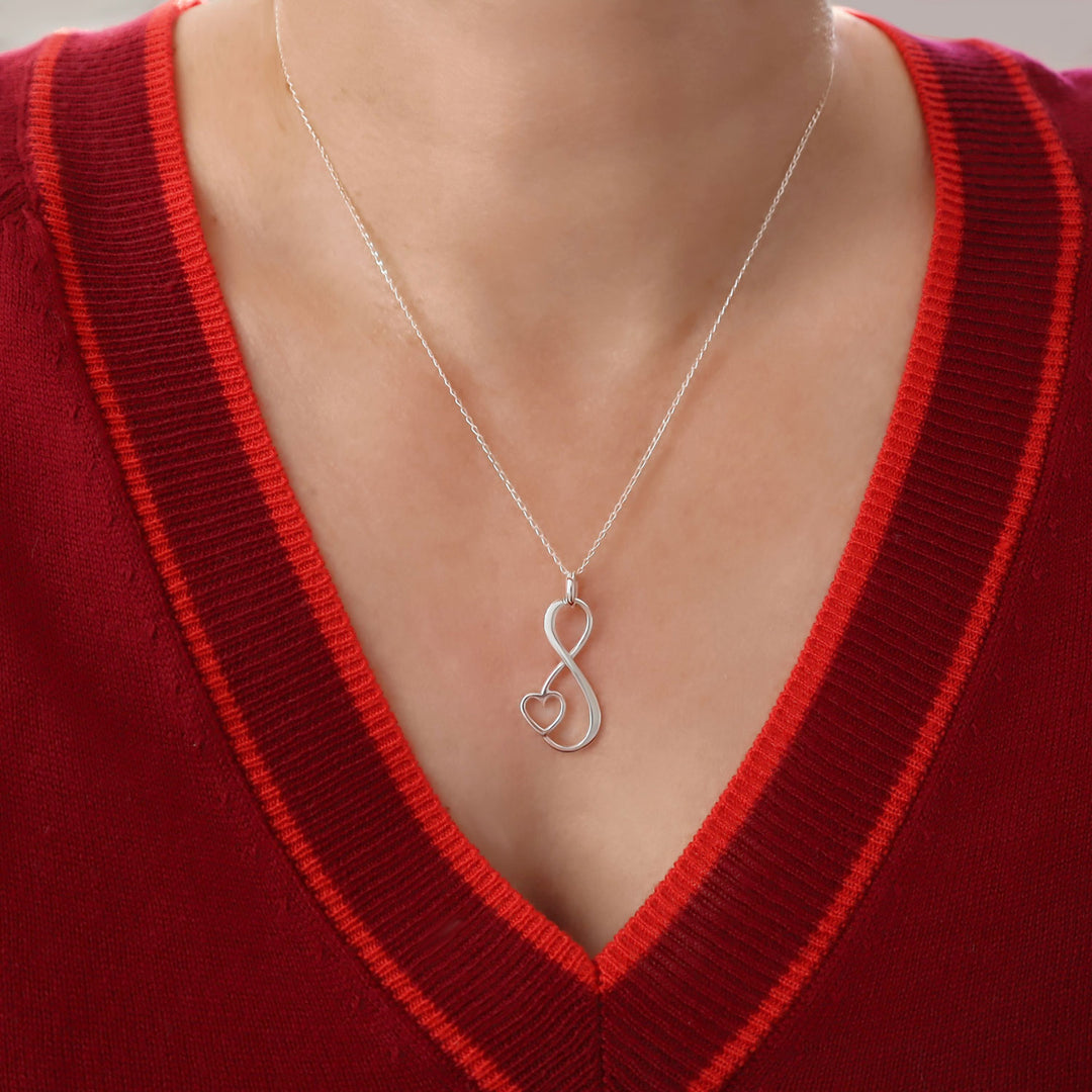 925 sterling silver necklace with a heart and infinity symbol pendant worn by a woman in  a red sweater.