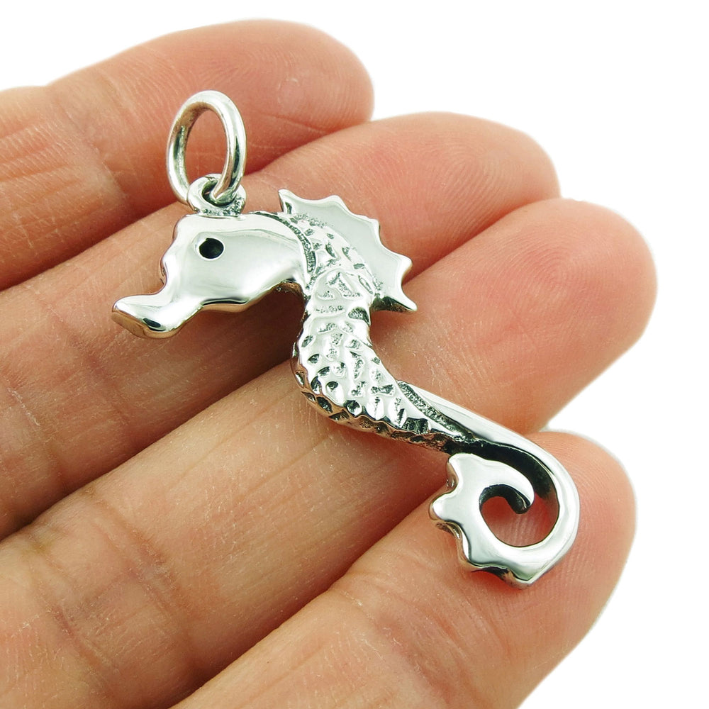 925 sterling silver seahorse pendant necklace for women held between fingers against a white background