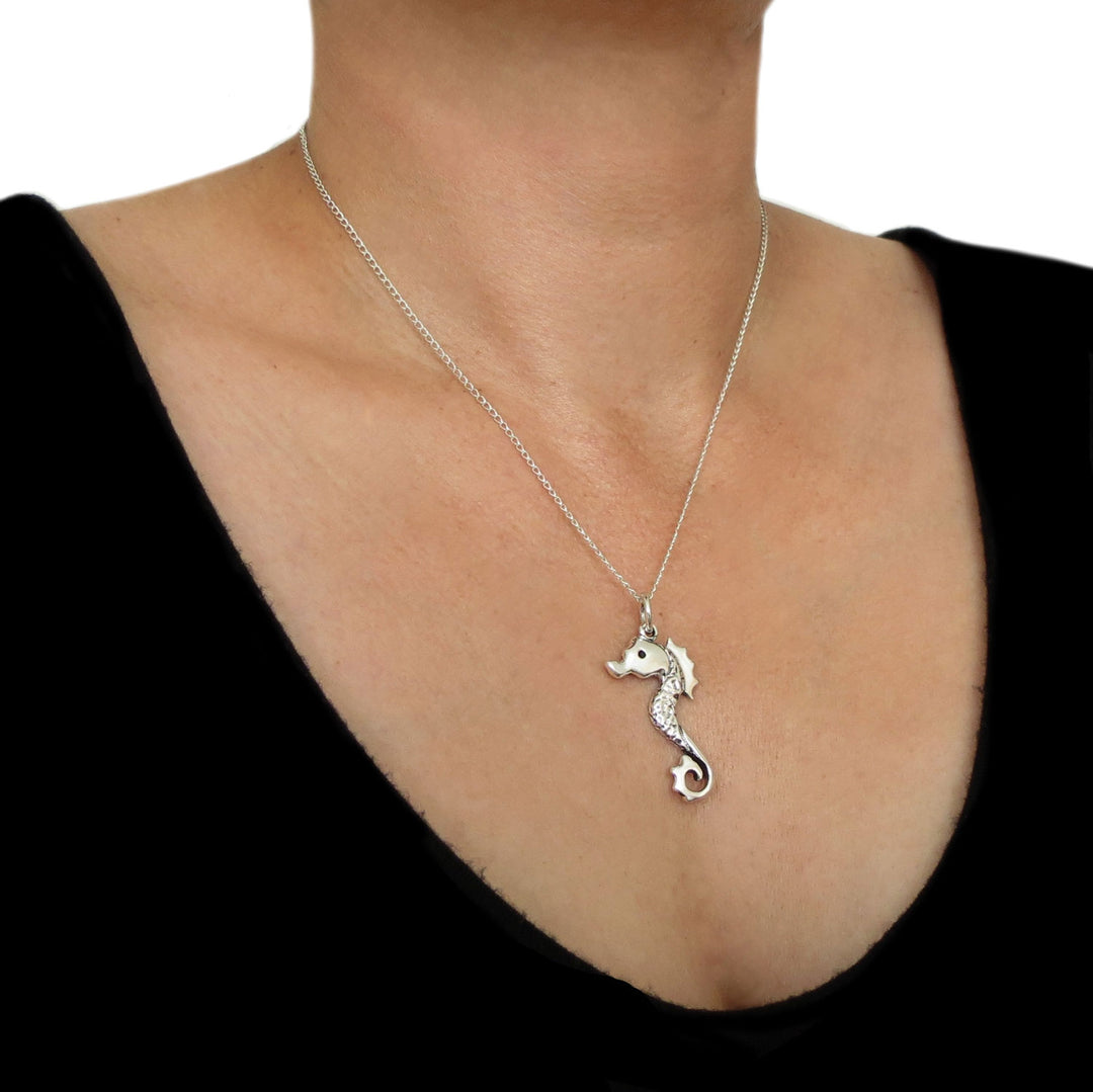 A large sterling 925 Mexican silver seahorse pendant and chain necklace on a woman wearing a black top