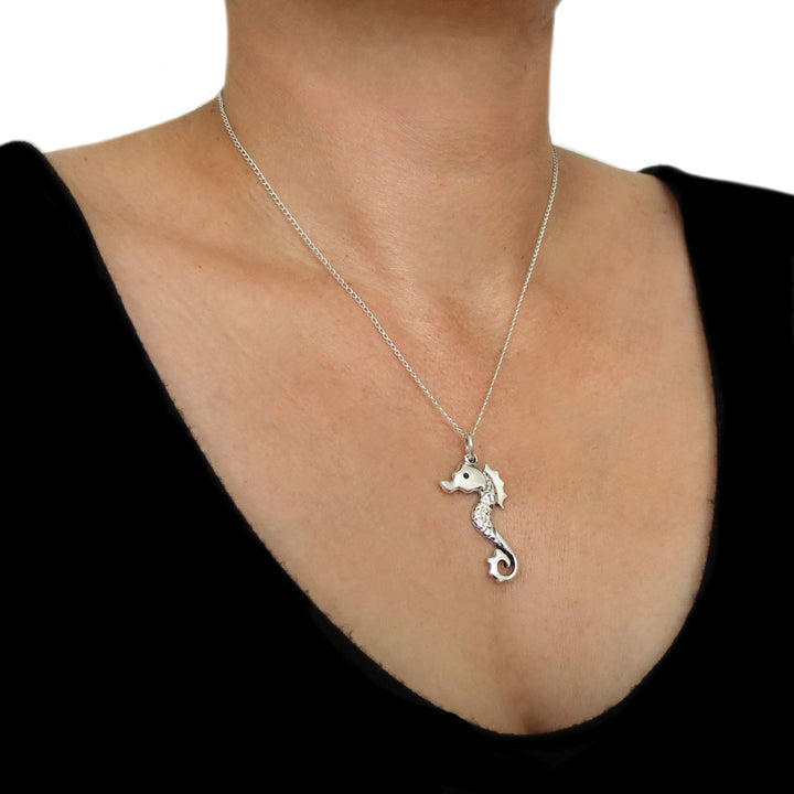 A large sterling 925 Mexican silver seahorse pendant and chain necklace on a woman wearing a black top
