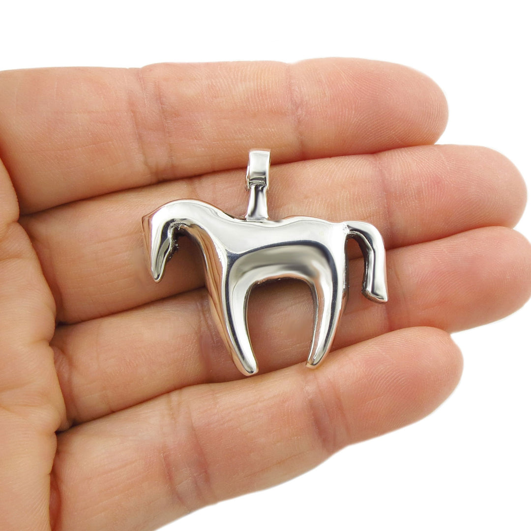 Large sterling silver odern horse pendant necklace held in a person's hand. 