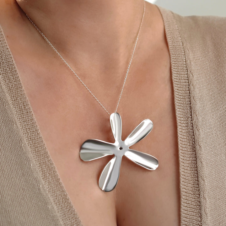 Silver necklace with a unique daisy flower pendant worn by a woman