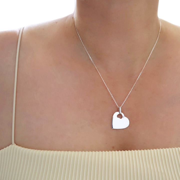 A sterling 925 silver heart-shaped pendant necklace worn on a model's neck, paired with a yellow ribbed top.