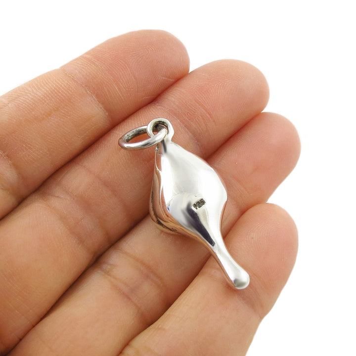 Silver calla lily flower pendant held upside down to show the 925 hallmark between fingers on a white background