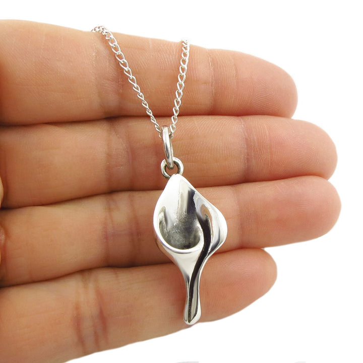 SSterlling 925 silver Mexican calla lily flower pendant necklace on a chain held between fingers against a white background