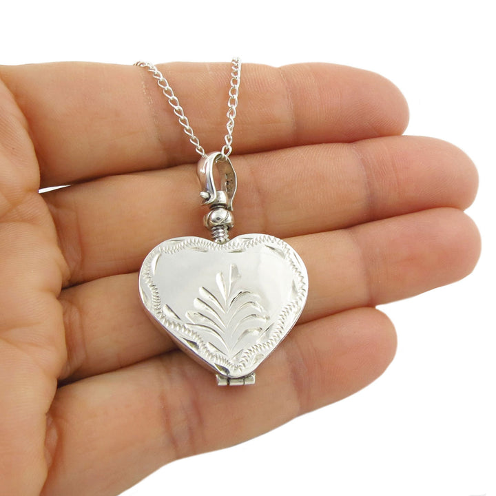 Laarge 935 sterling silver heart-shaped locket pendant necklace held in a hand on a white background