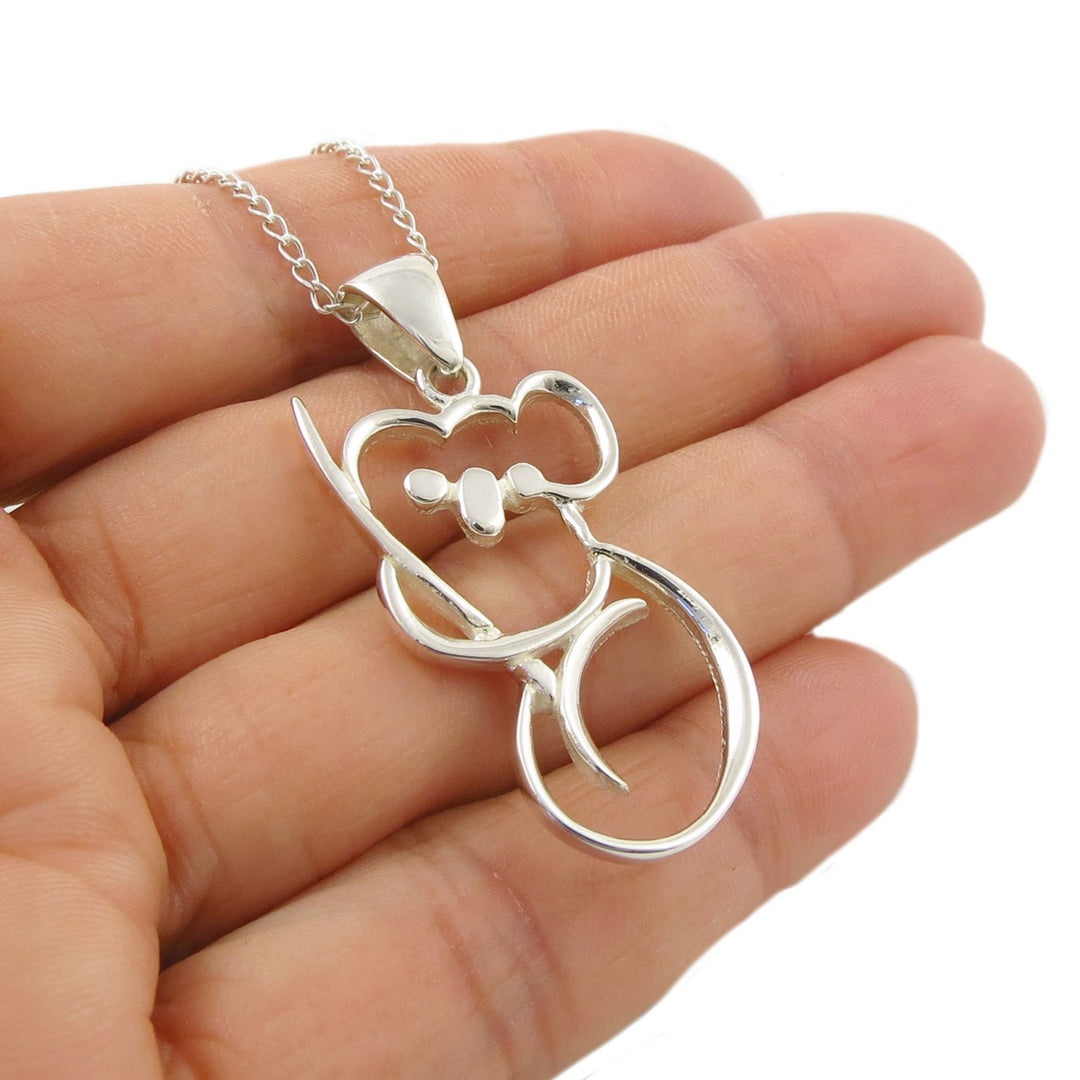 SSterling 925 Silver pendant shaped like a koala bear hanging on a curb chain held in a hand against a white background