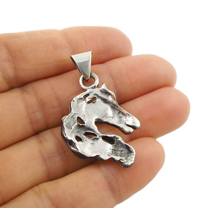 A large sterling 25 silver horse head pendant necklace held upside down in a person's hand