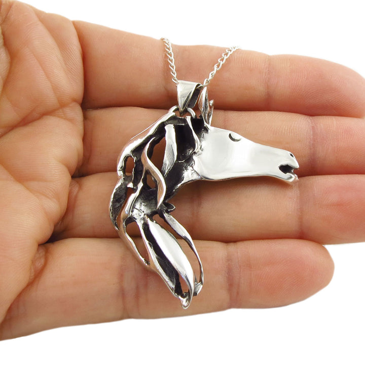 Equestrian sterling 925 silver horse head pendant and curb chain necklace held in a person's hand