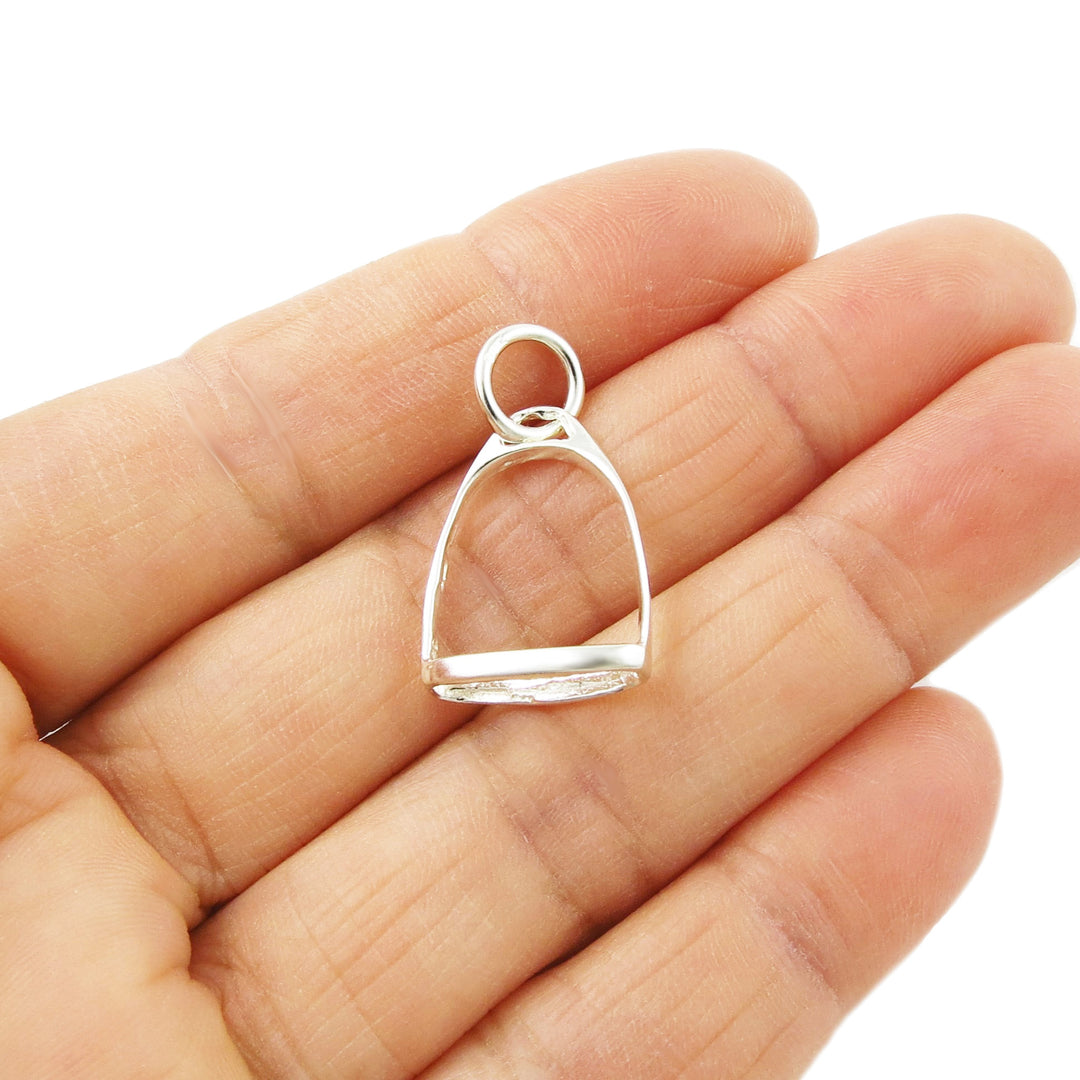 925 silver horse stirrup pendant held between fingers on a white background