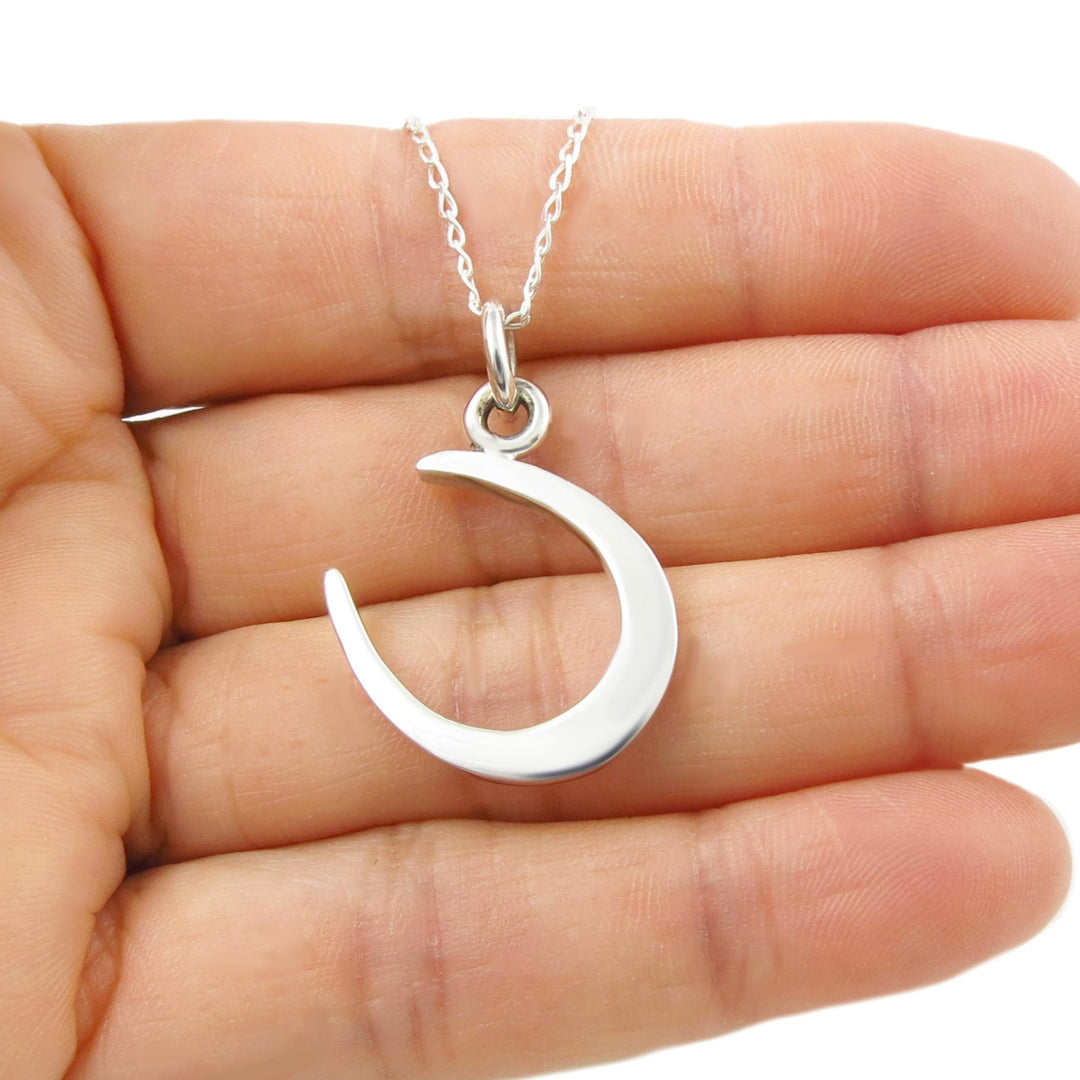 A silver horseshoe necklace held in a person's hand. 