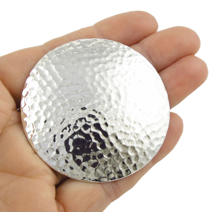 A large sterling 925 silver hammered pendant necklace held in a hand against a white background