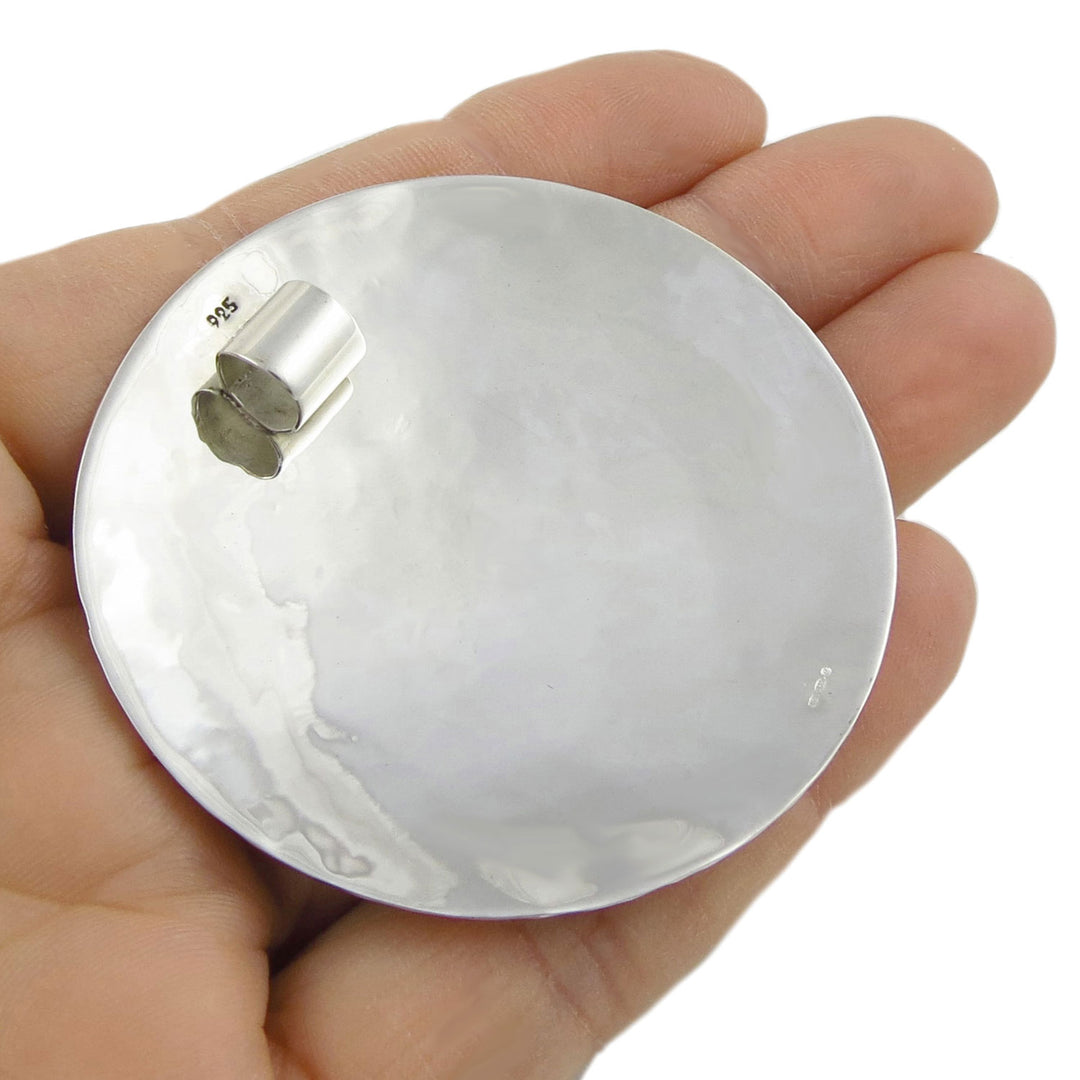A large sterling 925 silver pendant necklace held upside down in a hand to show the polished reverse and 925 hallmark