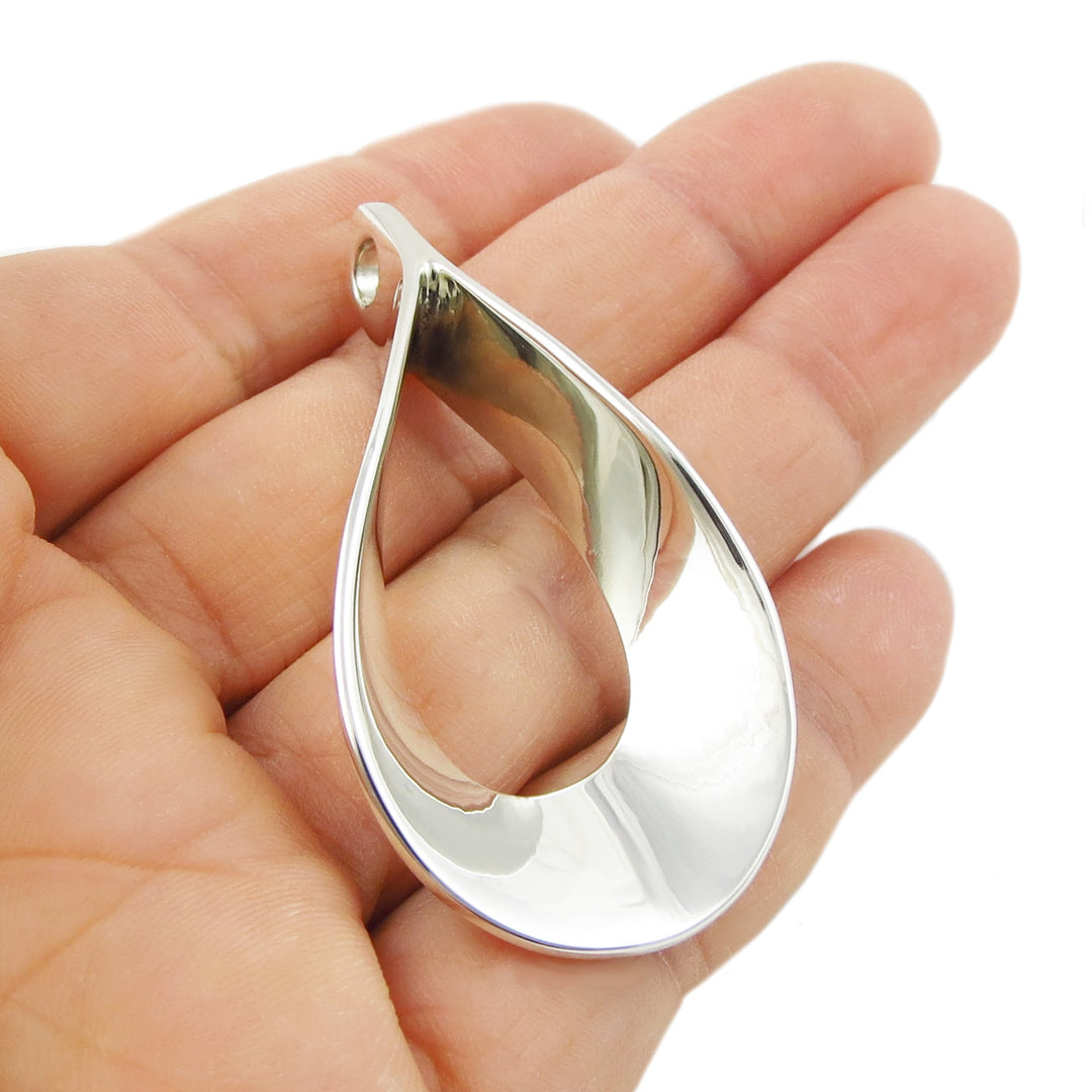 Silver teardrop-shaped pendant held in a hand against a white background