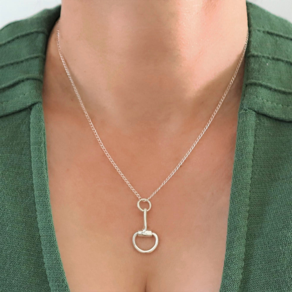 A sterling 925 silver solid equestrian snaffle horsebit pendant and chain necklace displayed on a woman's neck.