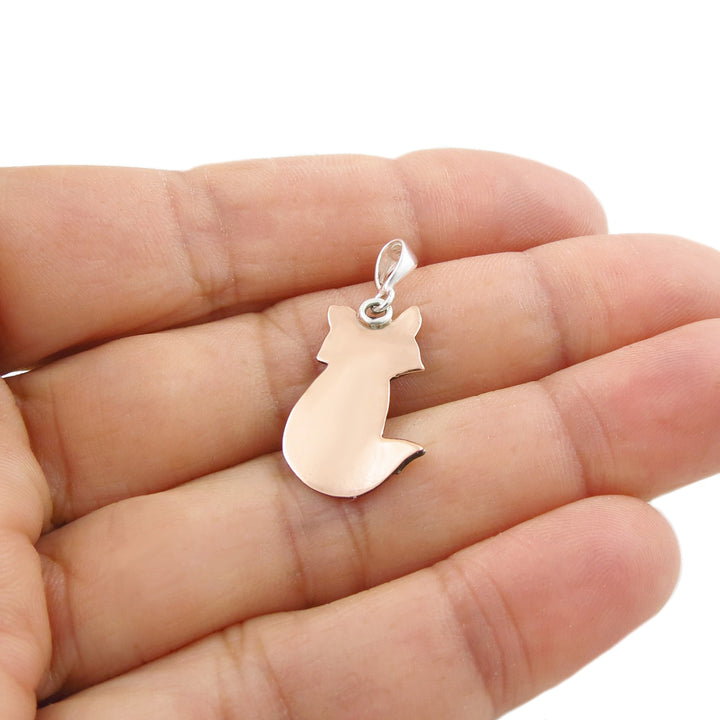 The reverse of a copper and 925 silver pendant in the hape of a fox held in a person's hand. 