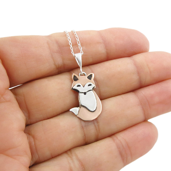 A person holding a two tone copper and 925 silver fox animal design unusual pendant and chain necklace in their hand