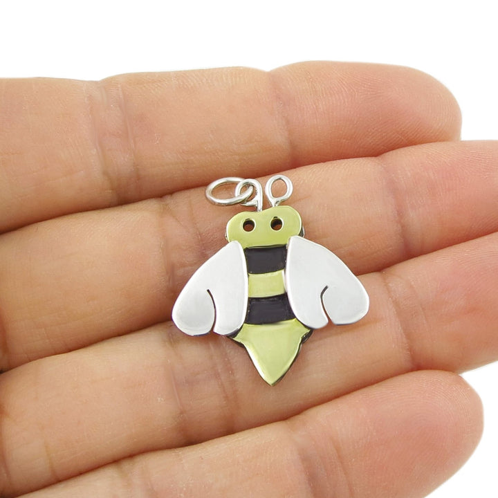 Bee-shaped charm held between fingers on a white background