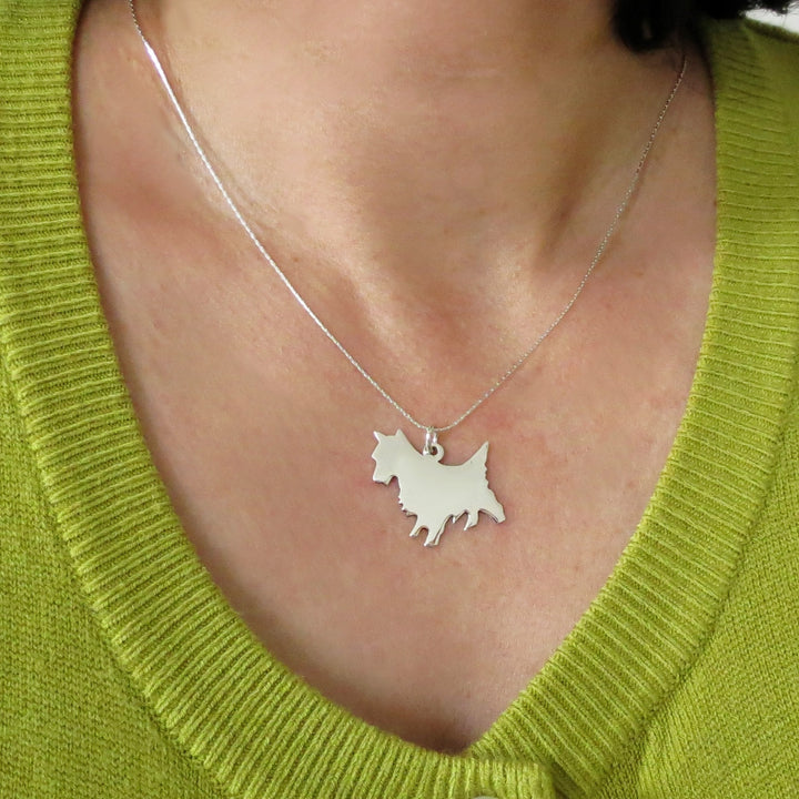 Large terrier dog pendant and chain necklace in 925 sterling silver with a polished finish worn by a woman in a lime green jumper