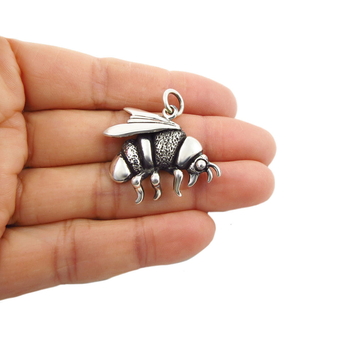 Large 925 sterling silver bumble bee pendant charm held between a woman's fingers on a white background