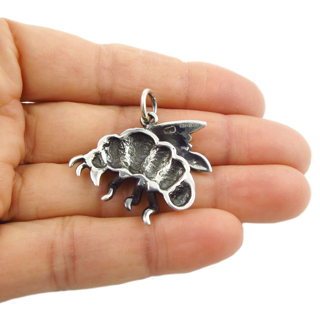 Reverse of a large sterling 925 silver bumble bee pendant jewellery held in a hand to show the UK Birmingham assay office laser hallmark.