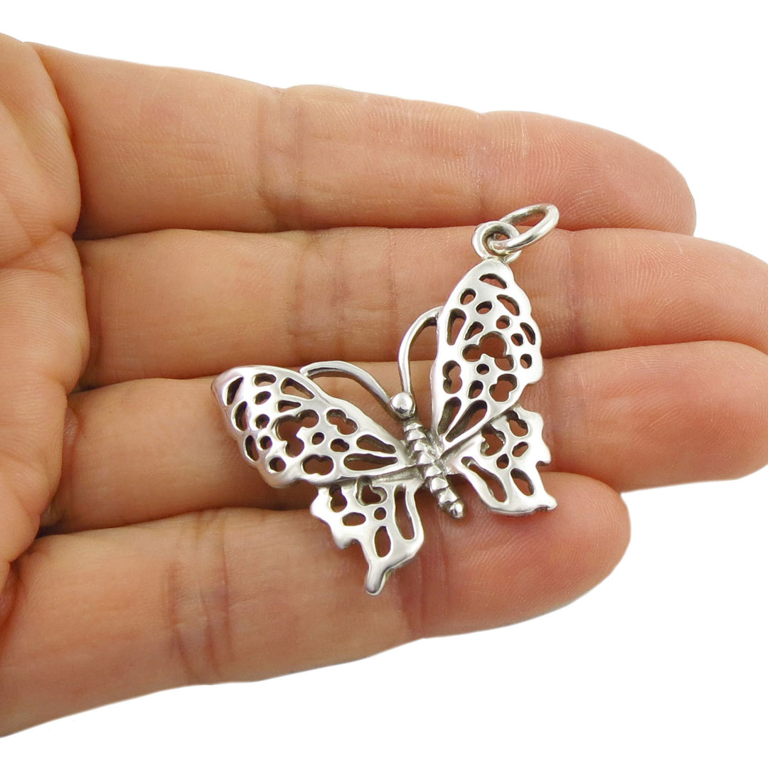 Large 925 sterling silver butterfly pendant jewellery held in a woman's hand on a white background