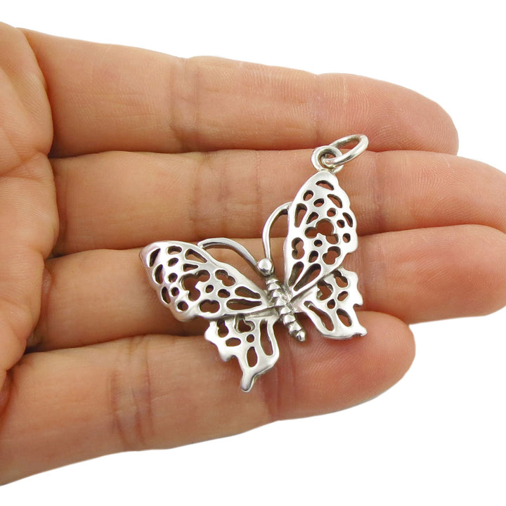 Large 925 sterling silver butterfly pendant jewellery held in a woman's hand on a white background