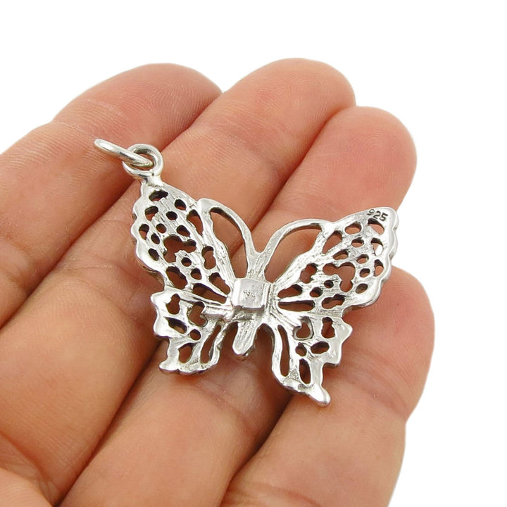 Sterling 925 silver butterfly pendant jewellery held in a hand against a white background