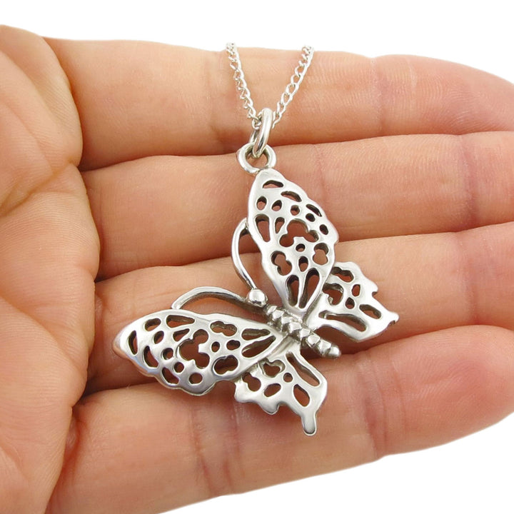 Large 925 silver butterfly pendant and chain necklace held in a woman's hand against a white background