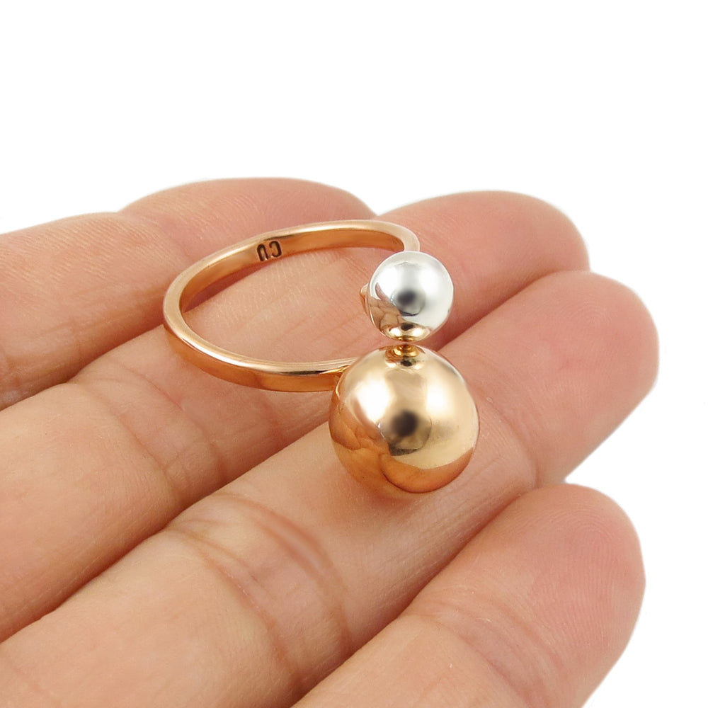 Copper and silver ball ring on a hand with a white background