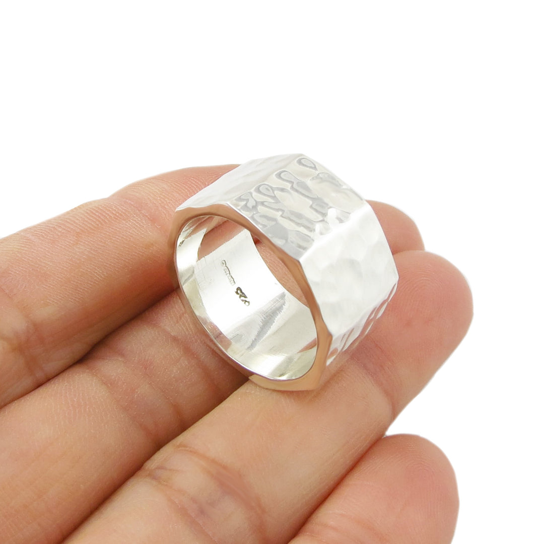 Sterling silver hammered ring held on a hand against a white background