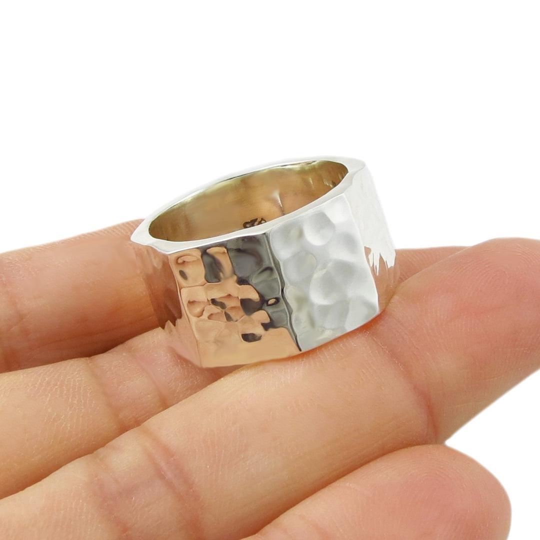 Silver ring with a textured surface on a finger against a white background