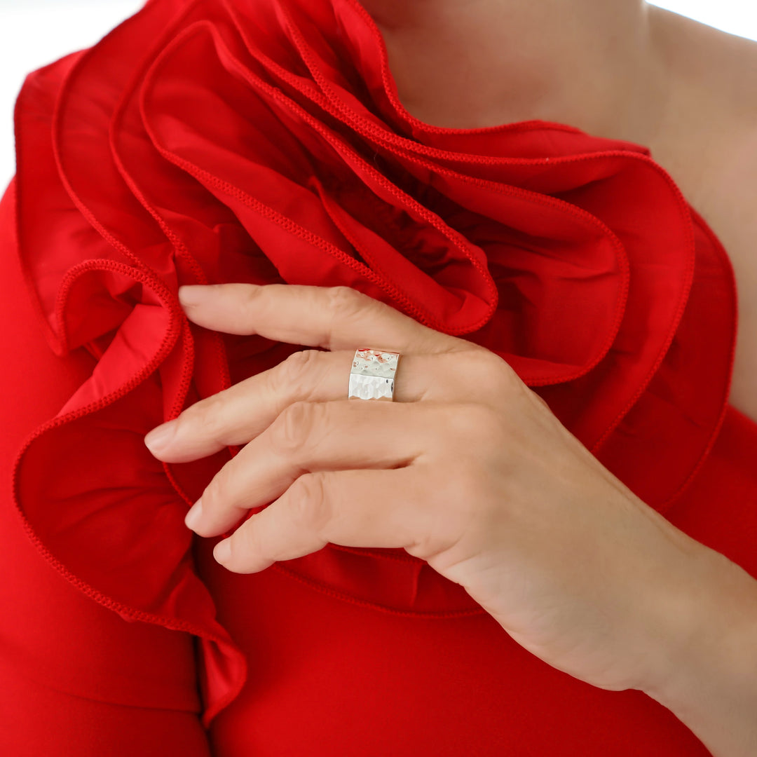 A woman in a red dress  wearing a solid silver ring with a hammered finish. 