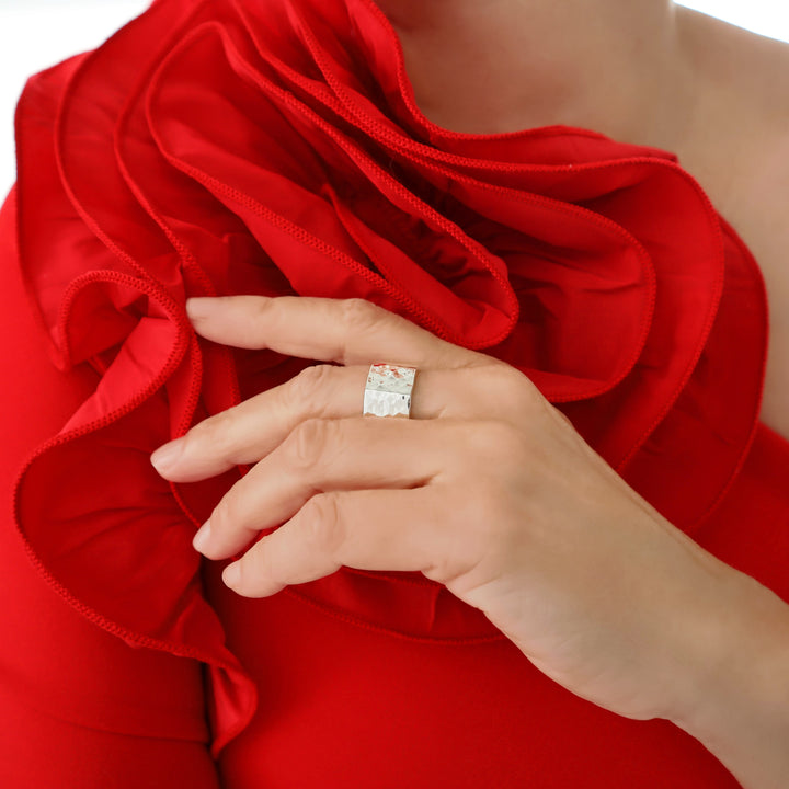 A woman in a red dress  wearing a solid silver ring with a hammered finish. 