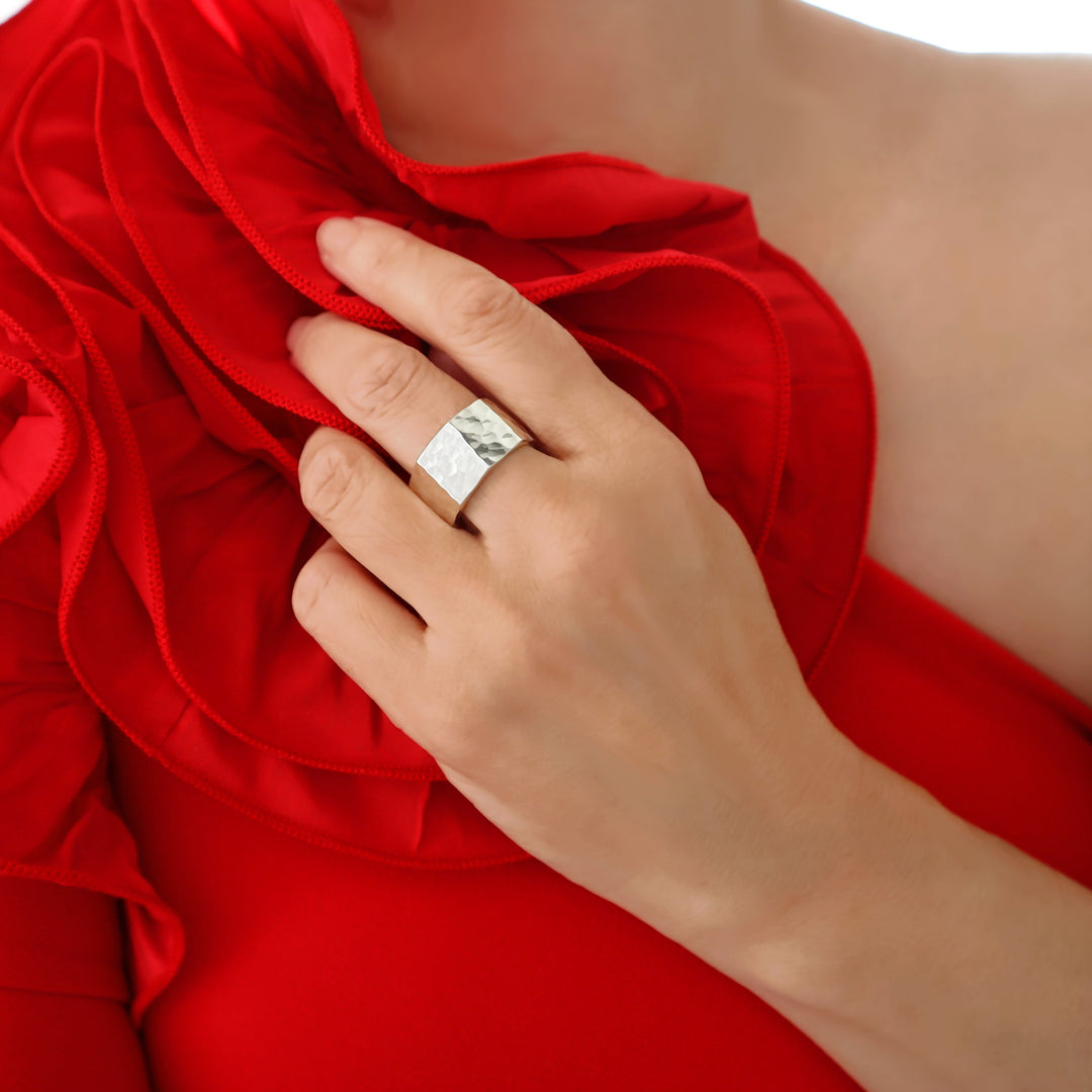 A woman in a red dress wearing a silver ring with a hammered finish. 