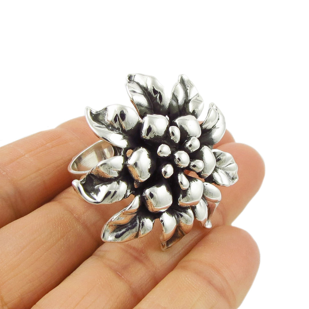 A large UK 925 sterling silver cocktail ring with a handmade large flower design, displayed on a person's hand.