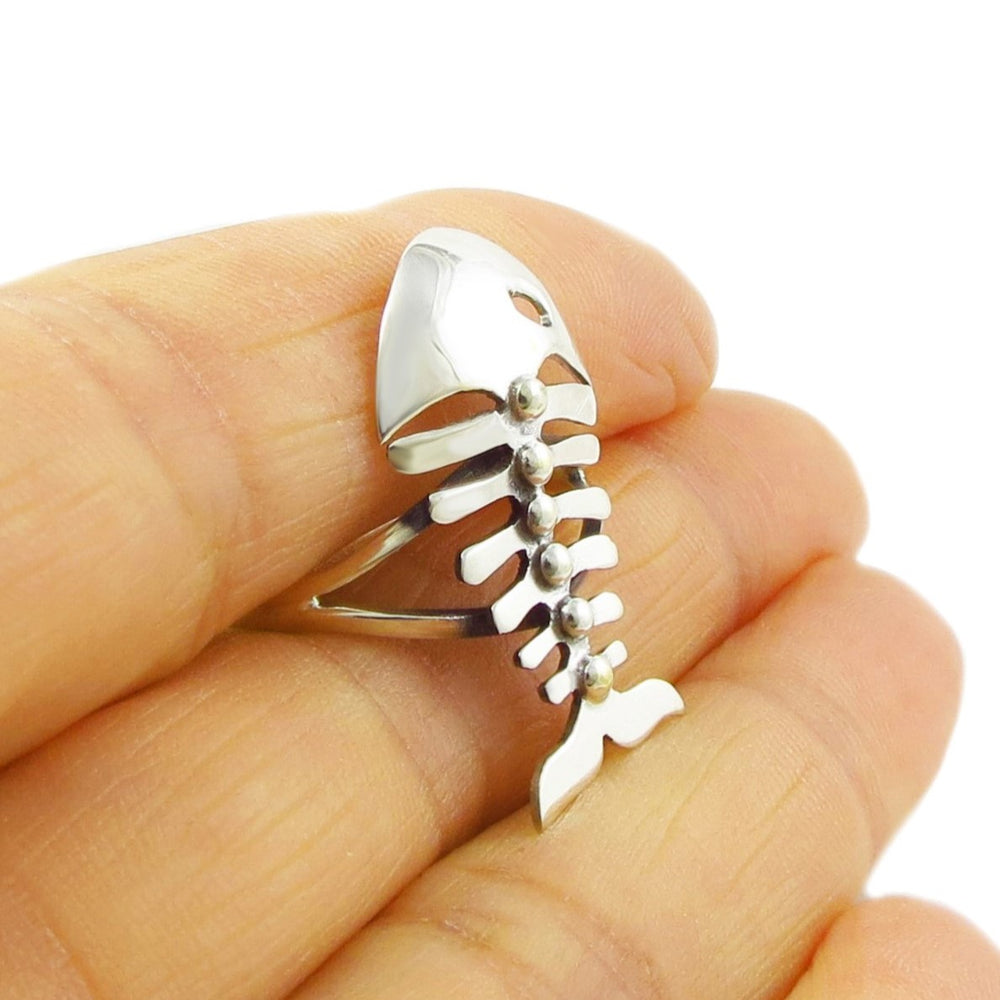 Large sterling 925 silver fish skeleton ring held between a woman's fingers. 