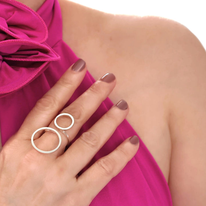 Close-up of a woman's hand wearing a large sterling silver ring with a pink garment in the background