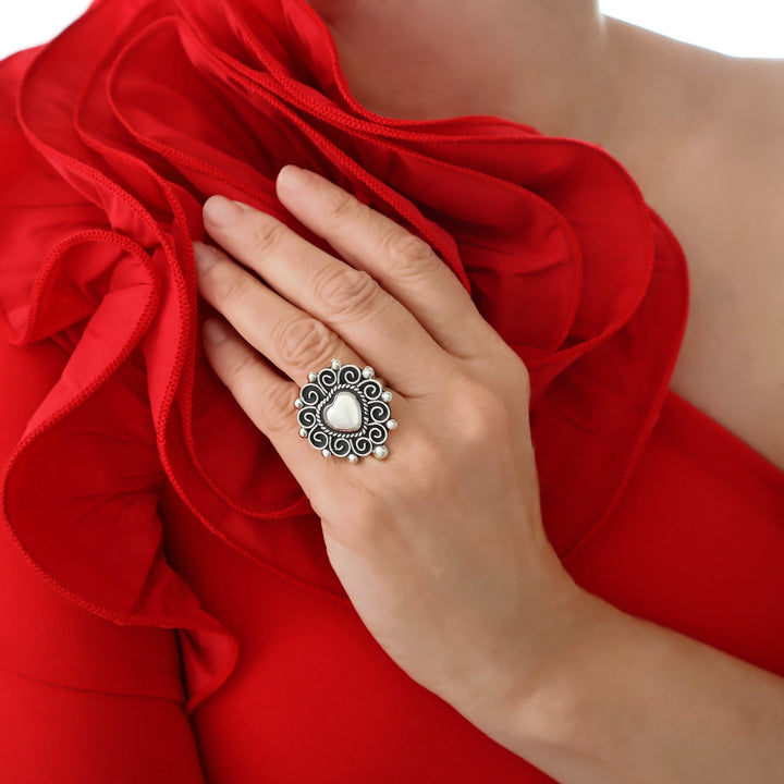 A woman in a red dress wearing a large Baroque style Taxco 925 sterling silver ring in the shape of a large heart