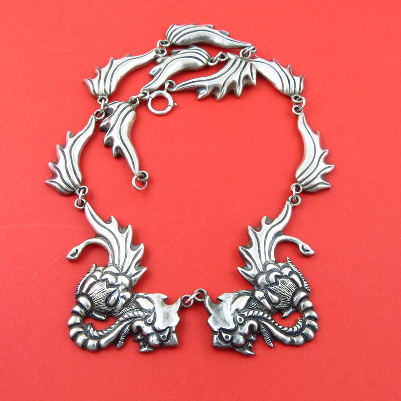 A Mexican Taxco 980 silver antique dragon collar necklace on a red background