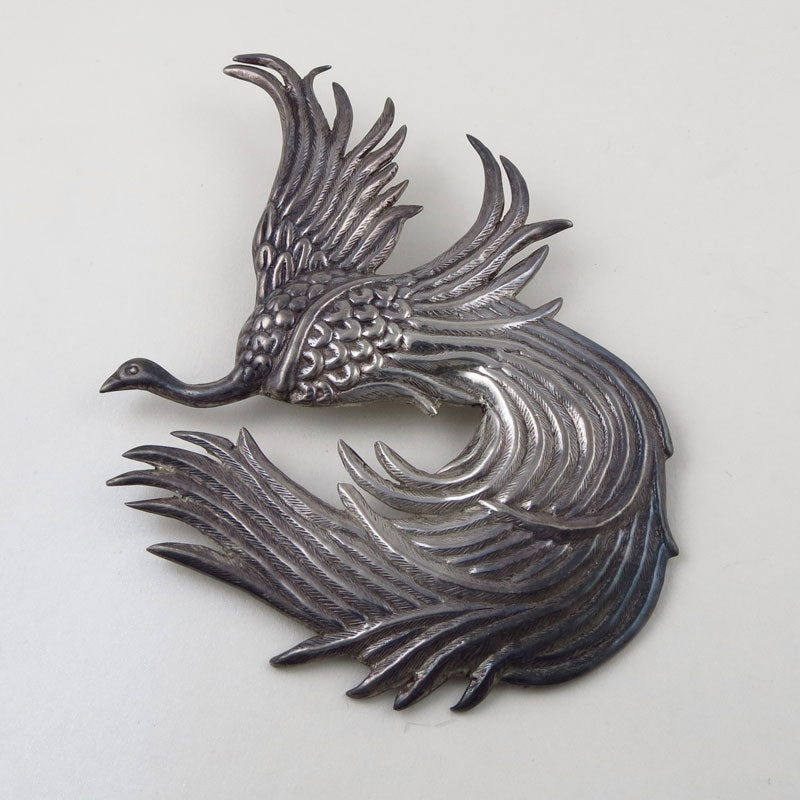 A large Hector Aguilar for Coro vintage handmade Mexican sterling silver peacock brooch pin on a grey background
