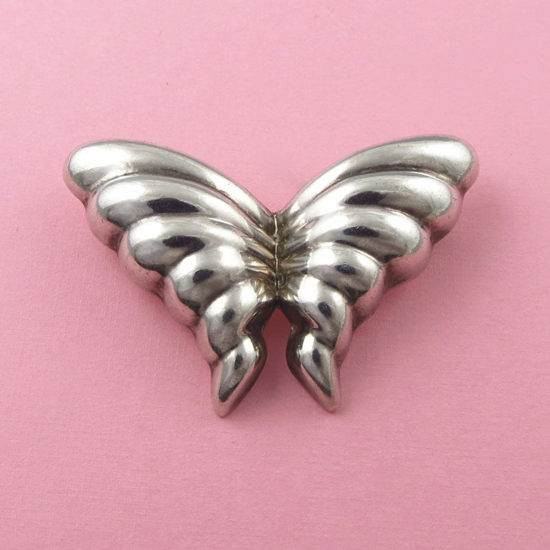 A vintage Tiffany & co puffed made in Mexico sterling silver butterfly brooch pin on a pink background