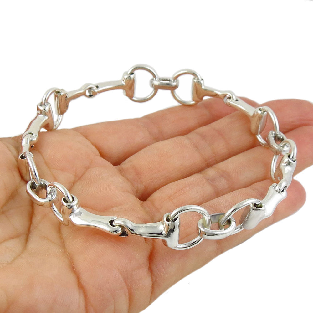 Large sterling silver equestrian horsebit snaffle riding tack bangle held in a person's hand 