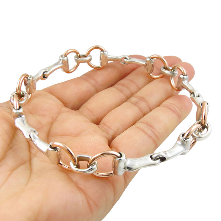 925 Silver and copper mixed metal horse bit snaffle design rigid bangle jewellery held in a hand against a white background