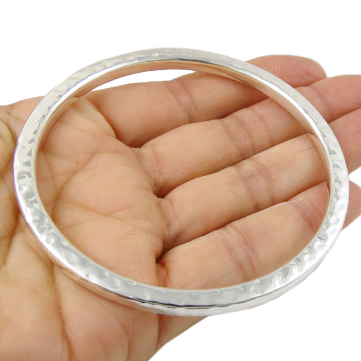 Hammered silver bangle on a hand against a white background