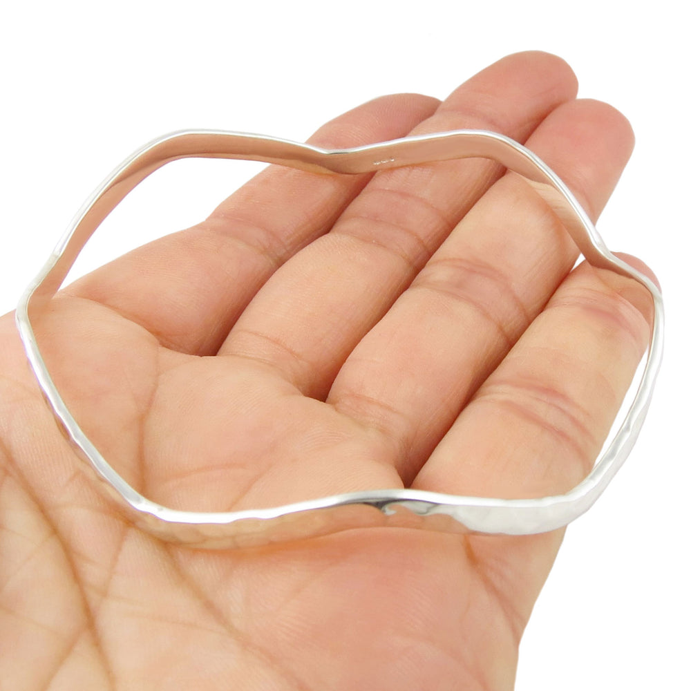 Silver bangle in the shape of an octagon  on a hand against a white background