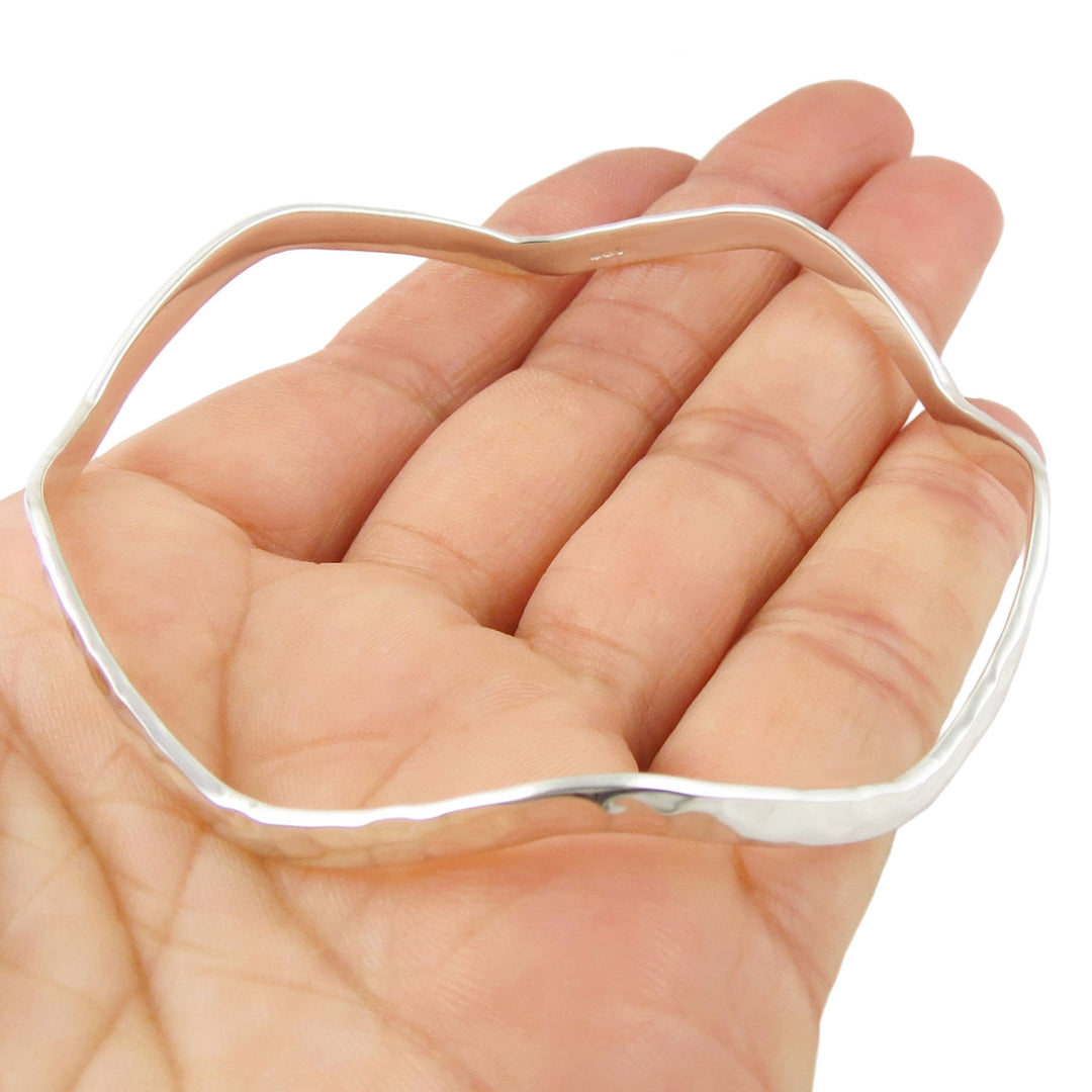 Silver bangle in the shape of an octagon  on a hand against a white background