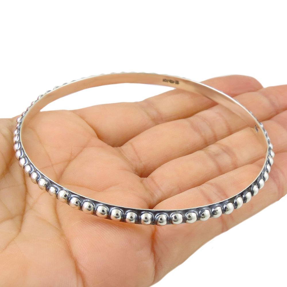 A large beaded sterling 925 silver bangle for women held in a persons hand