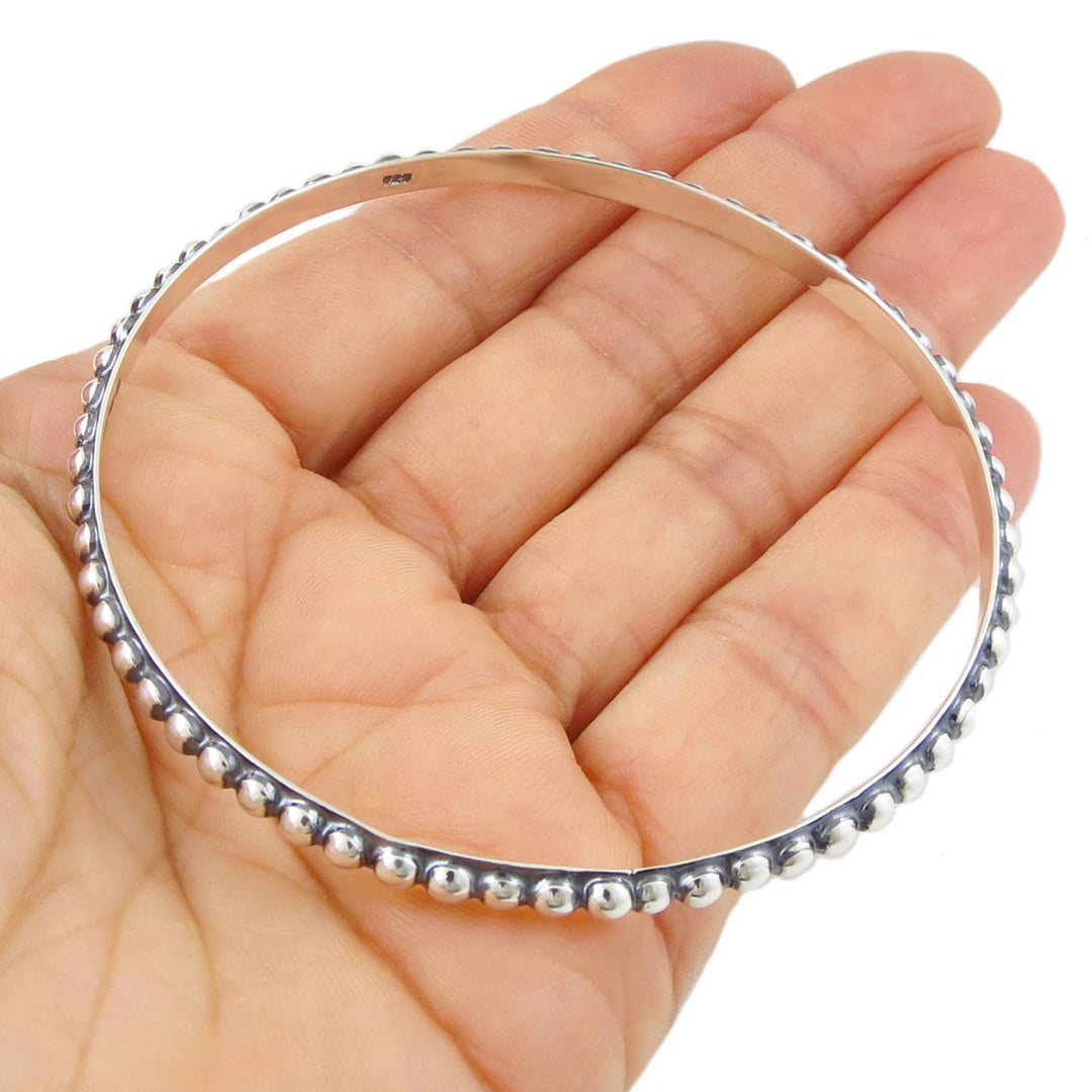 Sterling 925 silver UK hallmarked beaded bangle held in a hand against a white background