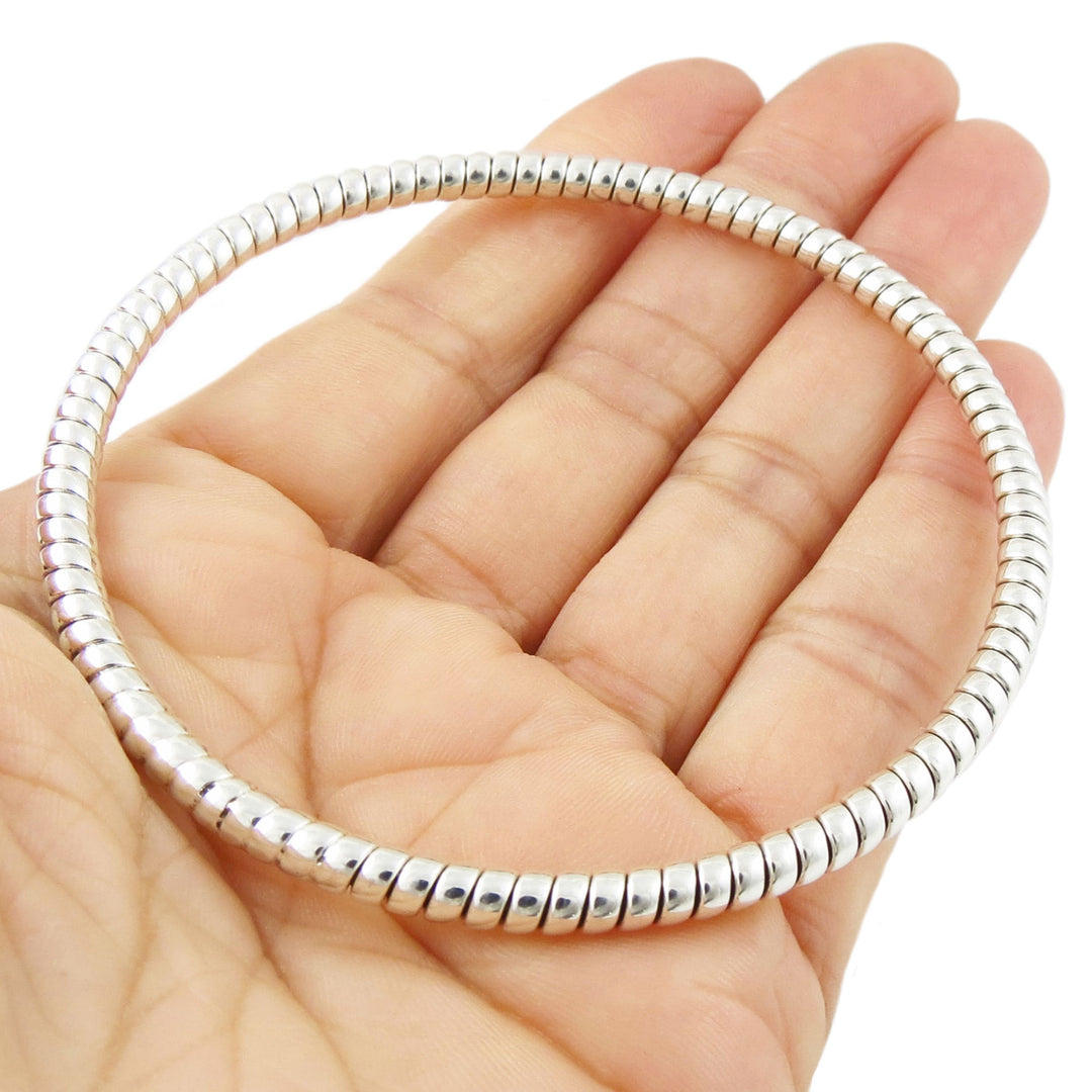 A hand holding a large circle bangle in 925 sterling silver with a twisted rope pattern